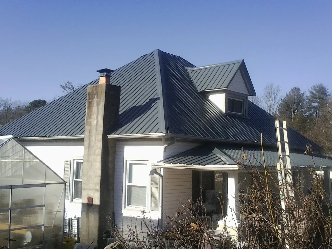 Dark blue standing seam metal roof on a white farmhouse with dormer — Slate & Tile Roof Repair by Roofing Brothers in Allensville