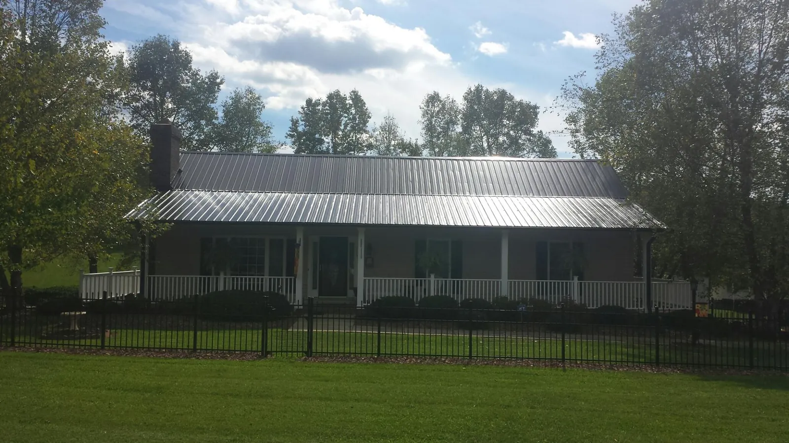 Gray metal roof on a brick ranch with a full width front porch — Gutter Guard Installation work by our crew in Allensville