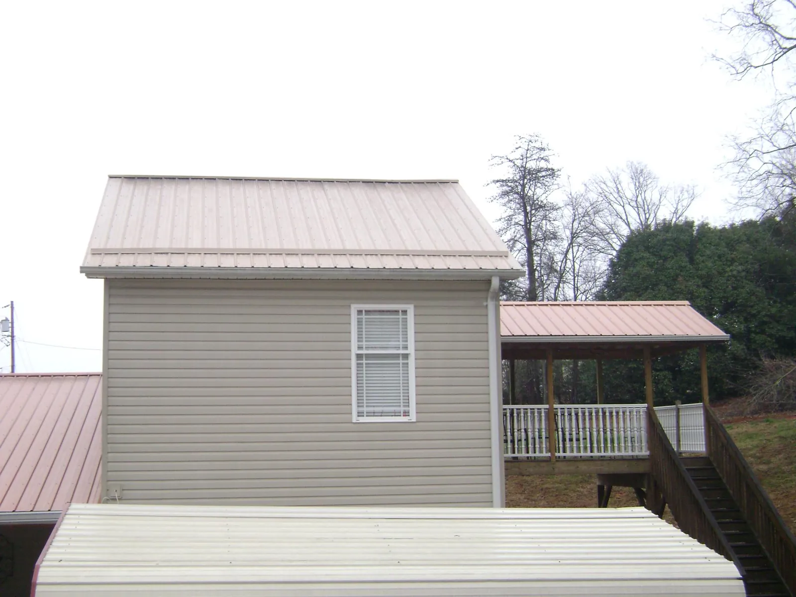Tan metal roofs on a two story addition and attached porch, from a Roof Replacement job in Allensville