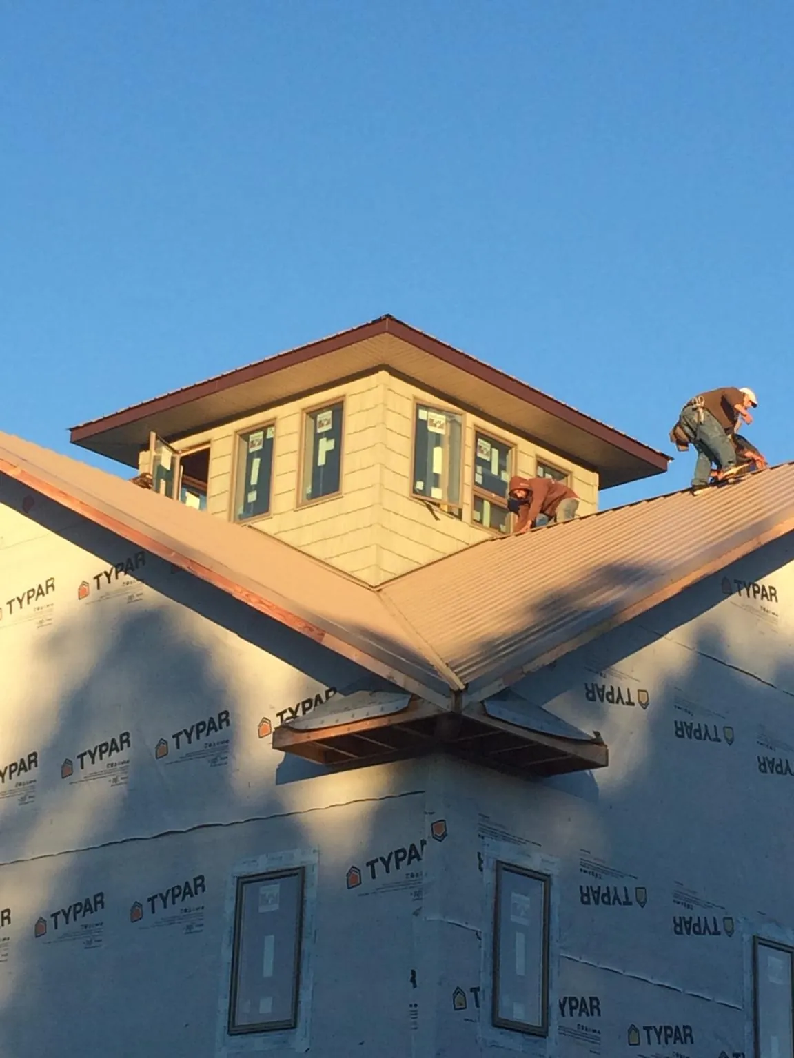 Roofers working around a rooftop cupola on a new metal roof at sunset — Roof Waterproofing in Allensville by Roofing Brothers